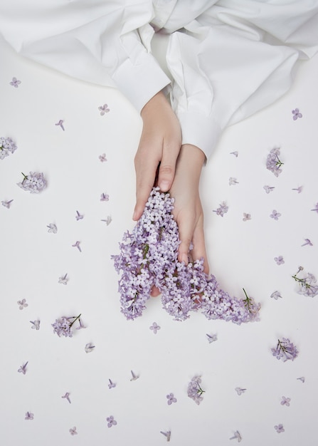 Produits Cosmétiques Naturels Pour Les Mains En Fleurs Et Pétales De Lilas. Hydrate Et Adoucit La Peau Des Mains. Des Fleurs Lilas Dépassent Des Manches Du Bras