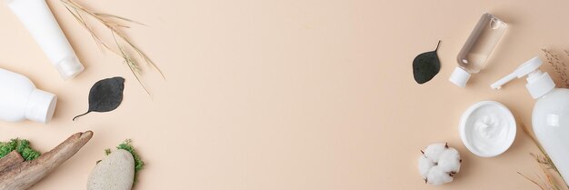 Produits cosmétiques pour le soin de la peau avec des fleurs et du bois sur un fond beige pastel