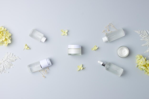 Photo produits cosmétiques pour le soin de la peau avec avec des fleurs sur fond gris espace de copie plat