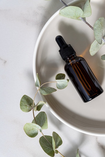 Produits Cosmétiques De Soins De La Peau Dans Un Compte-gouttes En Verre Foncé Avec Eucalyptus Sur Fond Clair. Mise à Plat, Espace De Copie