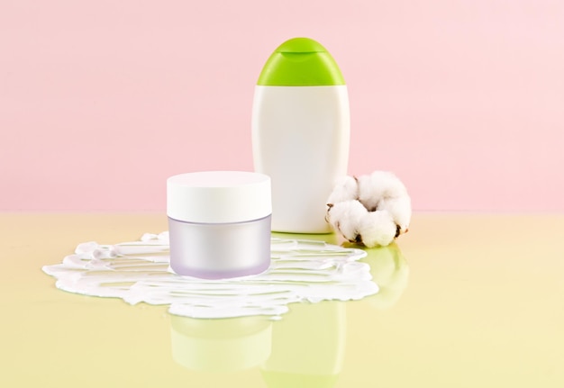 Produits cosmétiques SPA biologiques naturels sertis de fleur de coton séchée Vue latérale des produits de beauté pour le soin de la peau sur fond rose vert Mise en page de la publicité des cosmétiques Photo de haute qualité