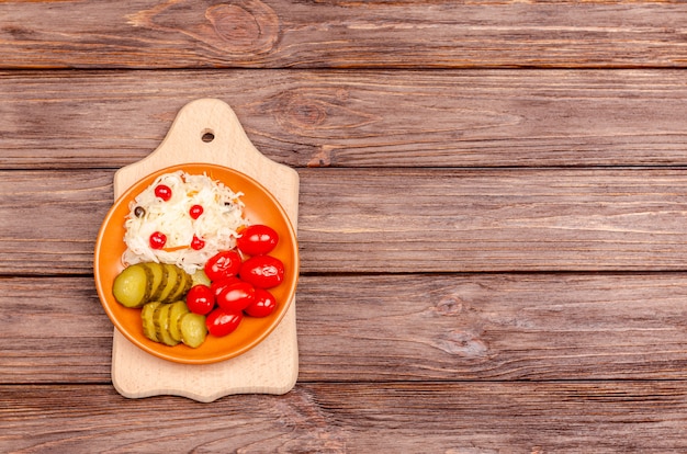 Produits fermentés faits maison sur une plaque - choucroute, tomates, cornichons sur une planche de bois