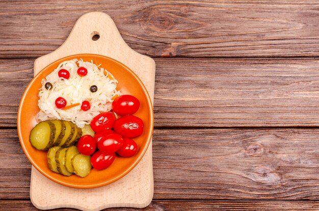 Produits fermentés faits maison sur une plaque - choucroute, tomates, cornichons sur une planche de bois