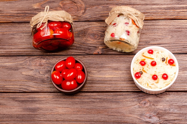 Produits laitiers fermentés savoureux faits maison sur des assiettes - choucroute, tomates marinées, sur table en bois, espace copie.