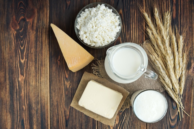 Les produits laitiers. Lait, kéfir, beurre, fromage cottage, œufs et fromage avec des épis de grain sur fond en bois foncé.