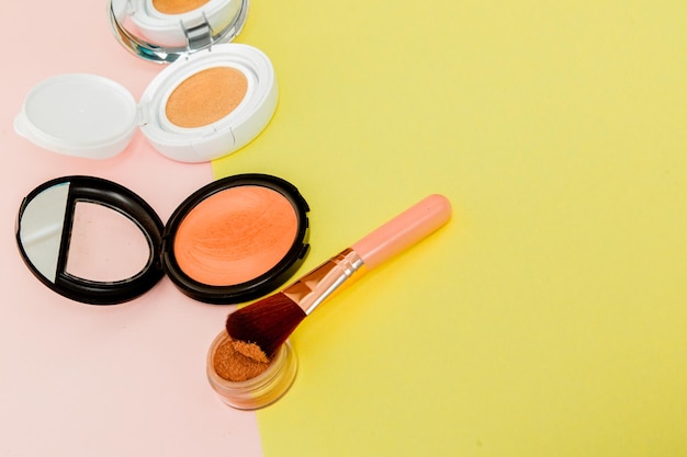 Produits de maquillage débordant sur un fond jaune et rose vif avec espace copie