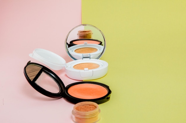 Les produits de maquillage se répandent sur un fond jaune vif et rose avec un espace de copie