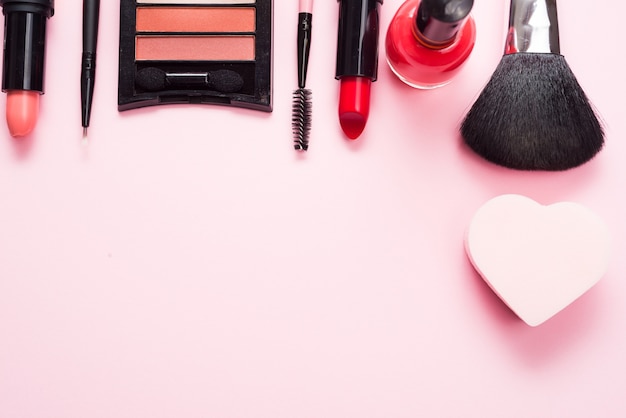 Produits de maquillage sur une table rose