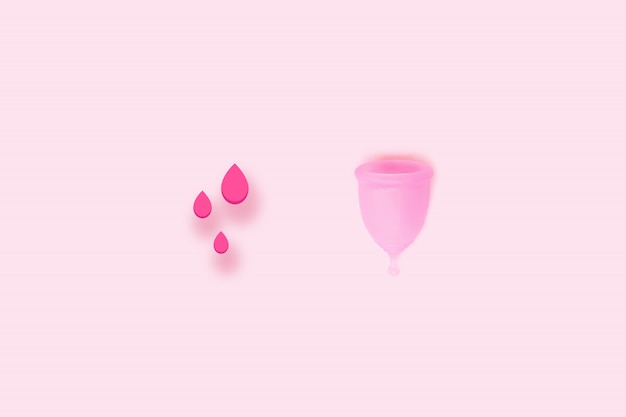 Produits De La Période D'hygiène Intime Féminine. Vue De Dessus Des Gouttes De Sang Et De La Coupe Menstruelle En Silicone Rose Sur Un Fond De Couleur.