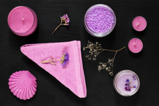 Produits de spa sels de bain lavande fleurs sèches savon crème cosmétique bougies et serviette concept violet violet plat sur fond noir vue du dessus