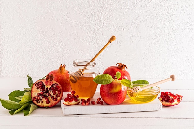produits traditionnels pour les vacances du Nouvel An juif pommes grenade miel sur un tableau blanc en bois et une table Le concept de Roshashan