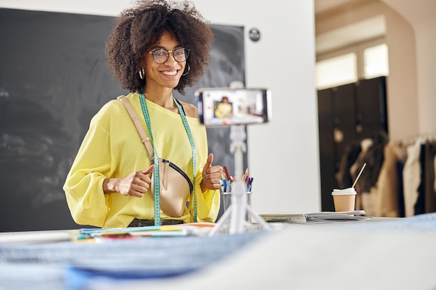 Un professeur afro-américain souriant tire un didacticiel pour un cours de design de mode à table
