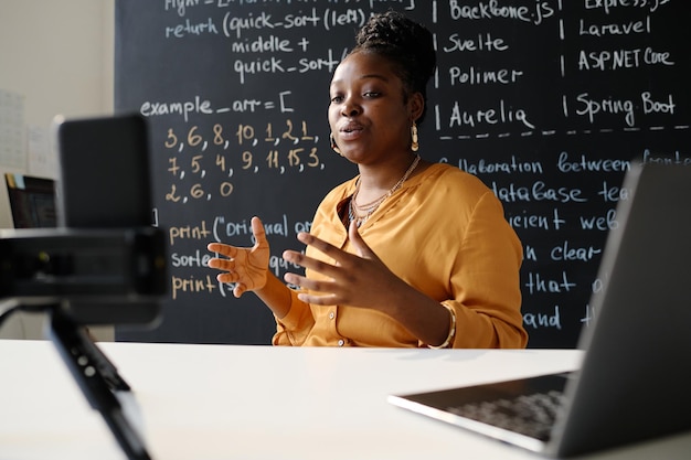 Professeur afro-américaine ayant son blog en ligne à ce sujet, elle est assise à table devant un smartphone