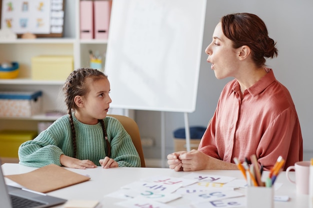 Professeur d'anglais enseignant à prononcer et à lire les mots de la petite fille alors qu'ils étaient assis à ...