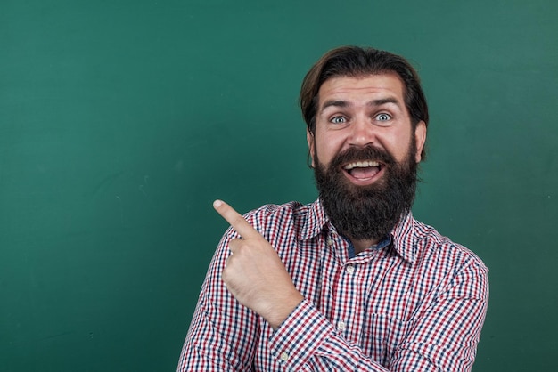 Professeur barbu mature à la leçon homme brutal travail en classe pointant le doigt sur le tableau noir se préparer à l'examen professeur d'université sur la leçon retour à l'école journée de la connaissance de l'éducation formelle