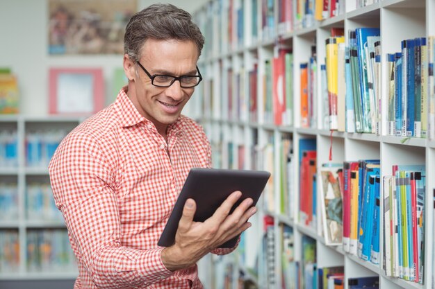 Professeur d'école heureux à l'aide de tablette numérique dans la bibliothèque