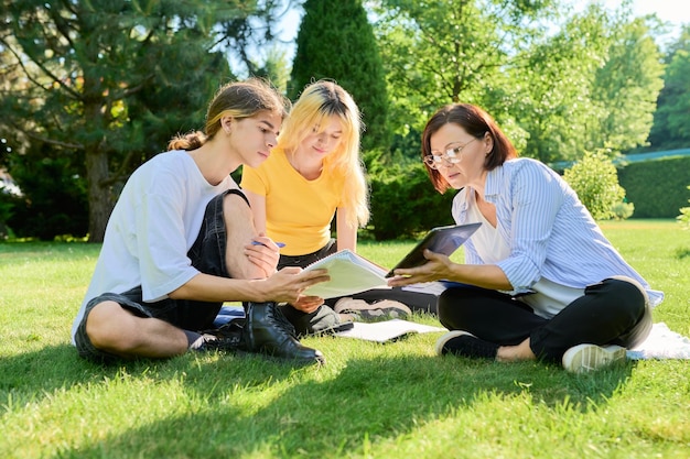 Professeur d'école psychologue travailleur social parlant à des adolescents assis sur l'herbe