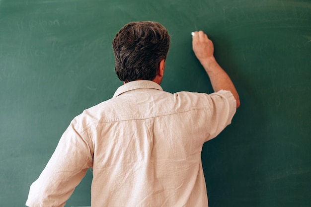 Le professeur écrit au tableau et explique une leçon.