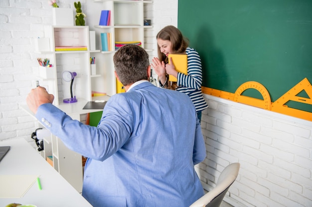 Professeur fâché criant à l'enfant à la violence de tableau noir