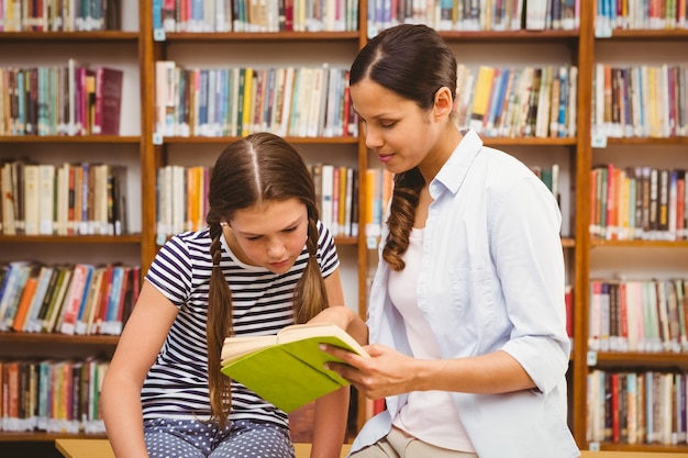 Professeur et fille livre de lecture dans la bibliothèque