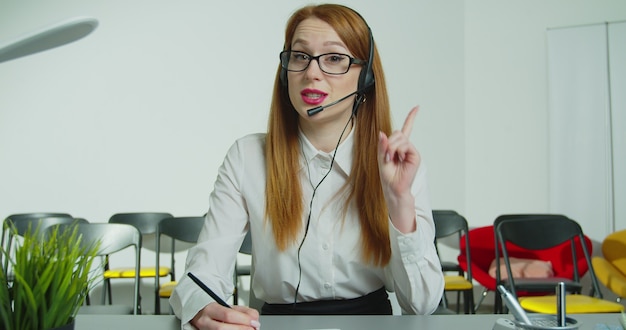 Professeur de formateur femme d'affaires dans le casque avec microphone regarde les enregistrements de la caméra webinaire en ligne master class