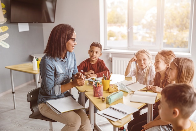 Professeur heureux ayant une leçon avec des enfants dans la salle de classe