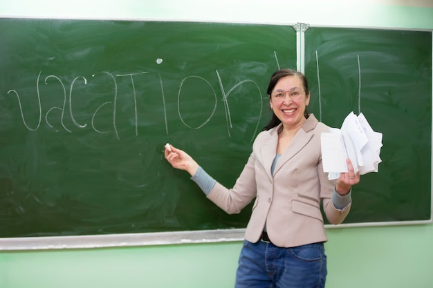 Le professeur heureux écrit le mot vacances sur le tableau noir