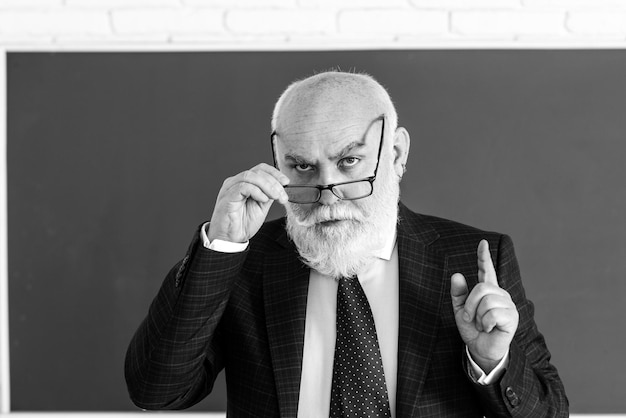 Professeur d'homme âgé sur un tableau blanc pendant la leçon d'enseignement à l'enseignement collégial et savoir