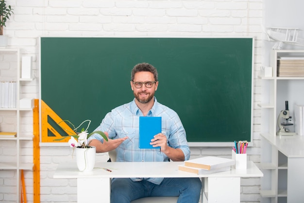 Professeur d'homme avec des livres et professeur de tableau sur la leçon au concept d'enseignement collégial et de connaissances