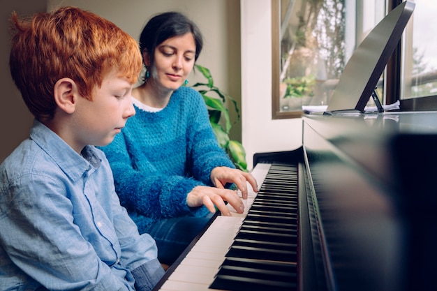 Professeur de piano femme enseignant un petit garçon à la maison des leçons de piano. Mode de vie familial passer du temps ensemble à l'intérieur. Enfants avec vertu musicale et curiosité artistique. Activités musicales éducatives.