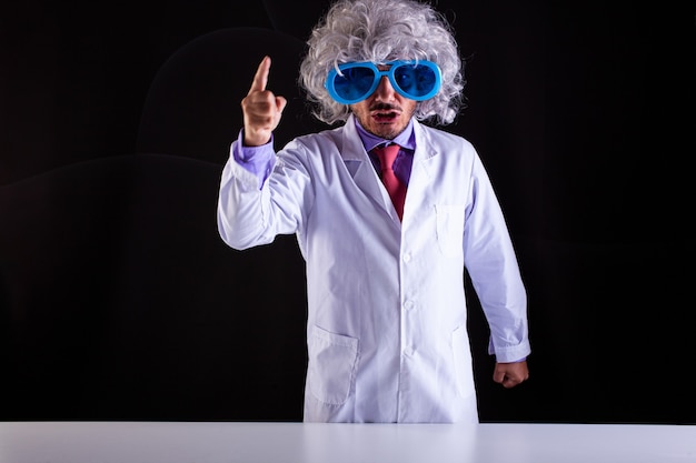 Professeur de sciences en colère en blouse blanche avec des cheveux hirsutes dans des lunettes drôles avec le doigt levé