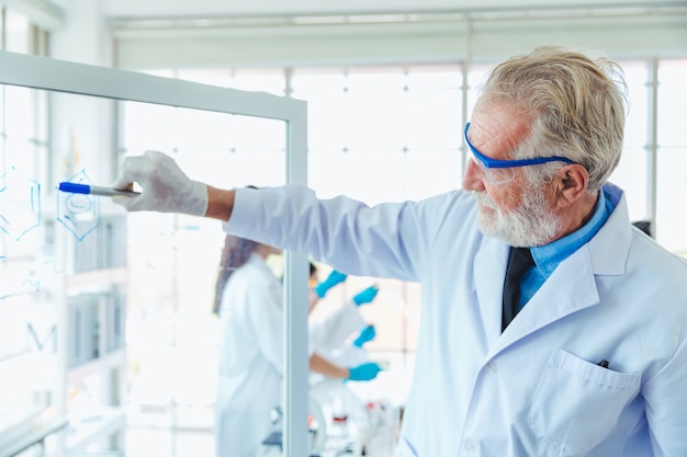 Professeur de sciences hommes travaillant avec des produits chimiques de panneau de verre transparent en laboratoire