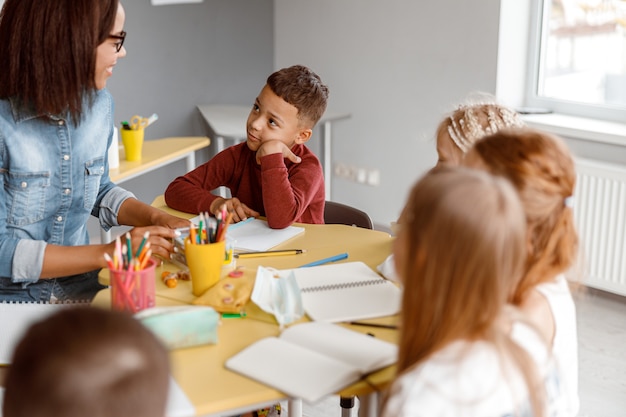 Professeur de sourire ayant une leçon avec des enfants dans la salle de classe