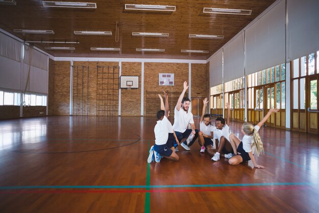 Professeur de sport et écoliers jouant dans un terrain de basket