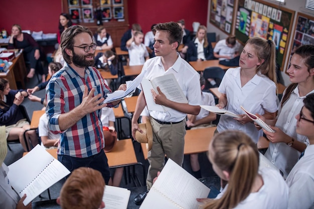 Professeur de théâtre menant des étudiants tenant des livrets