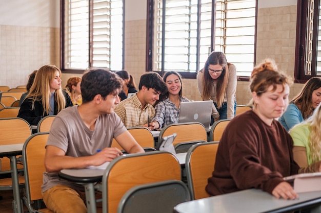 Professeur d'université expliquant individuellement à ses étudiants à sa table en classe