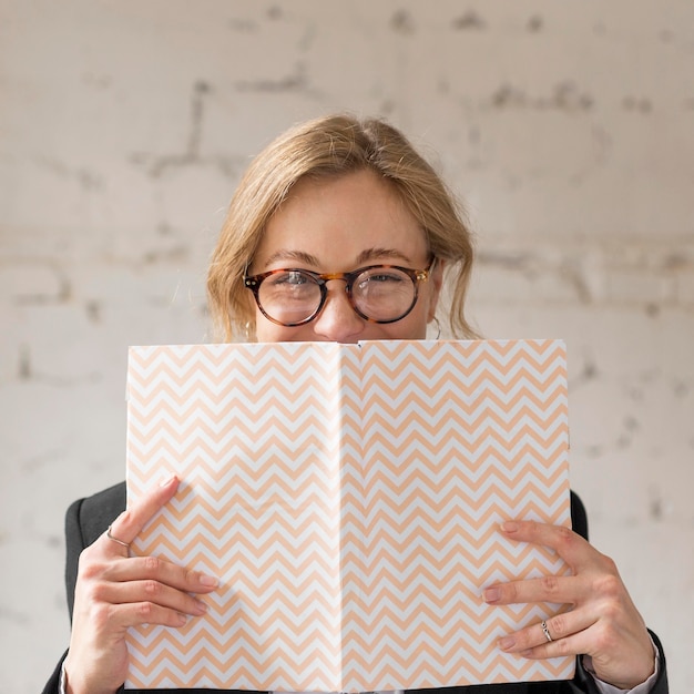 Professeur de vue de face couvrant le visage avec livre