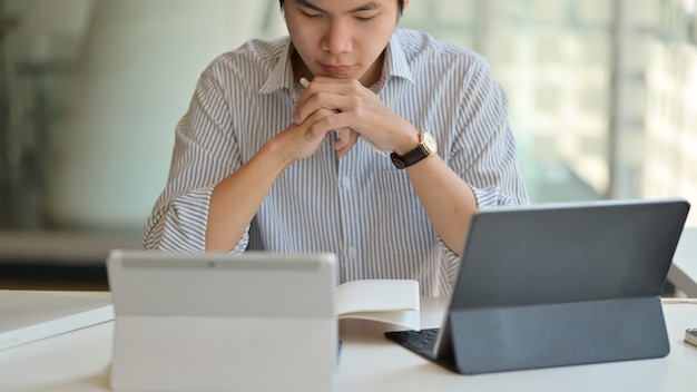 Professeurs masculins se préparant à enseigner en ligne avec une tablette numérique.