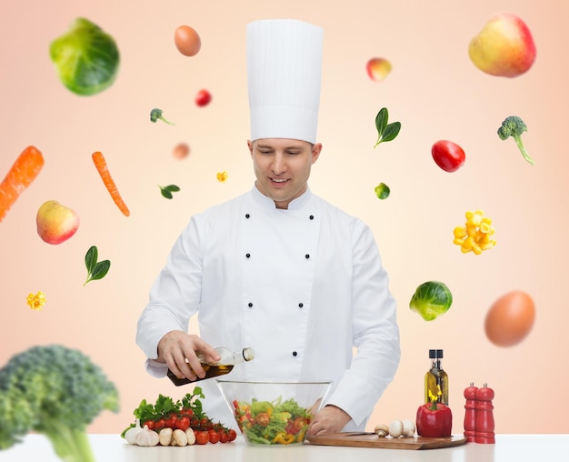 profession, régime végétarien, concept de nourriture et de personnes - chef masculin heureux cuisinant une salade de légumes sur fond beige avec des légumes qui tombent
