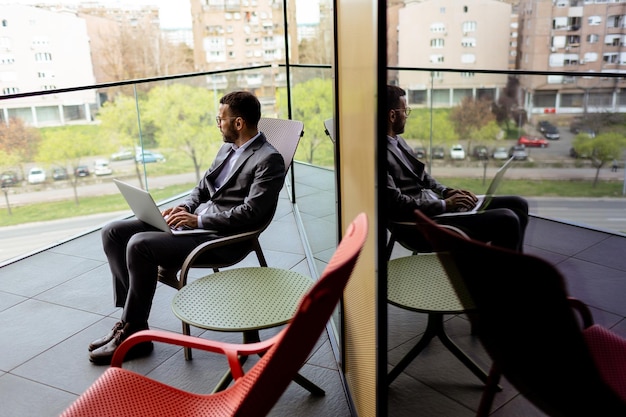 Un professionnel d'affaires occupé à travailler sur un ordinateur portable sur un balcon de bureau urbain moderne