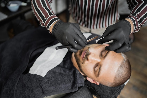 Professionnel dans un salon de coiffure faisant du bon travail, le jeune homme est sombre et brutal avec un spécial