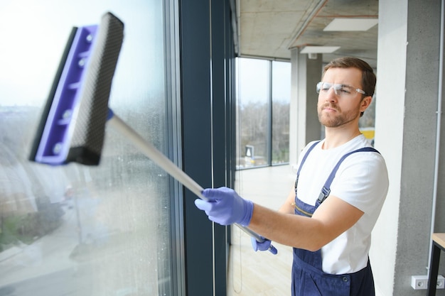 Photo un professionnel du service de nettoyage en combinaison nettoie les fenêtres et les vitrines d'un magasin avec un équipement spécial