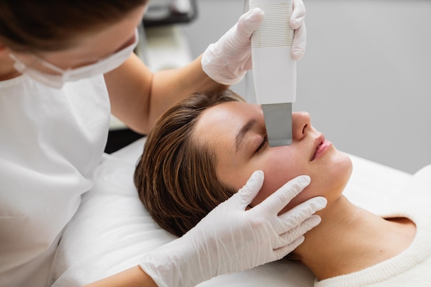 Un professionnel qualifié administre un traitement facial pendant que le client se détend sur un lit de traitement