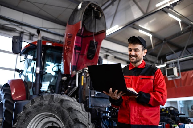 Professionnel de service debout à côté de la machine tractrice et tenant un outil de diagnostic portable