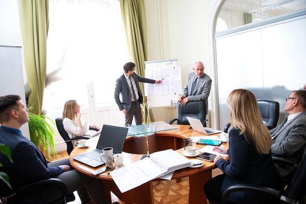 Des professionnels d'affaires prospères présentant un nouveau projet avec leurs collègues dans un bureau moderne