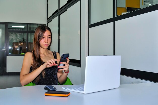Professionnels de l'entreprise. Jeune fille entreprenante, analysant les données à l'aide d'un ordinateur portable et d'un téléphone portable.