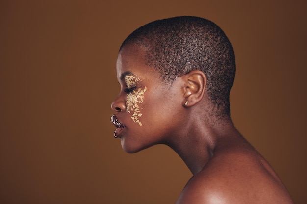 Photo profil artistique d'une femme noire avec un maquillage doré et un arrière-plan flou, peinture pailletée et cosmétiques shine glow et modèle africain en studio pour la mode beauté et la liberté esthétique dans les soins de la peau de luxe