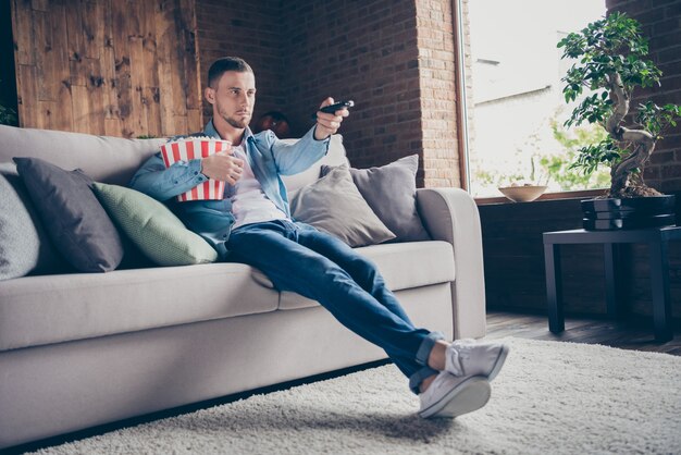 Profil beau mec séjour de détente à la maison manger du pop-corn s'asseoir canapé confortable