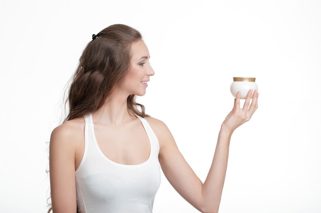 Profil de belle femme tenant le pot de crème cosmétique