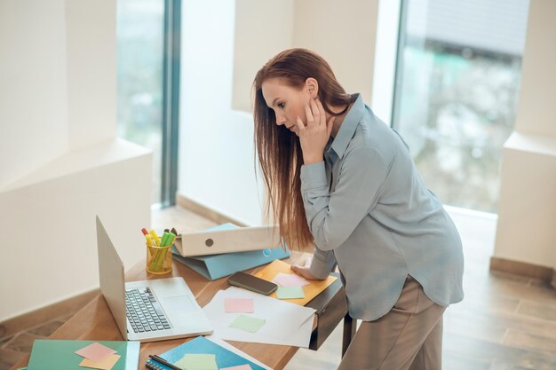 Profil d'une femme pensive regardant penchée sur un bureau